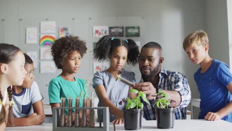 video de un feliz maestro afroamericano y una clase de alumnos diversos durante la lección de biología