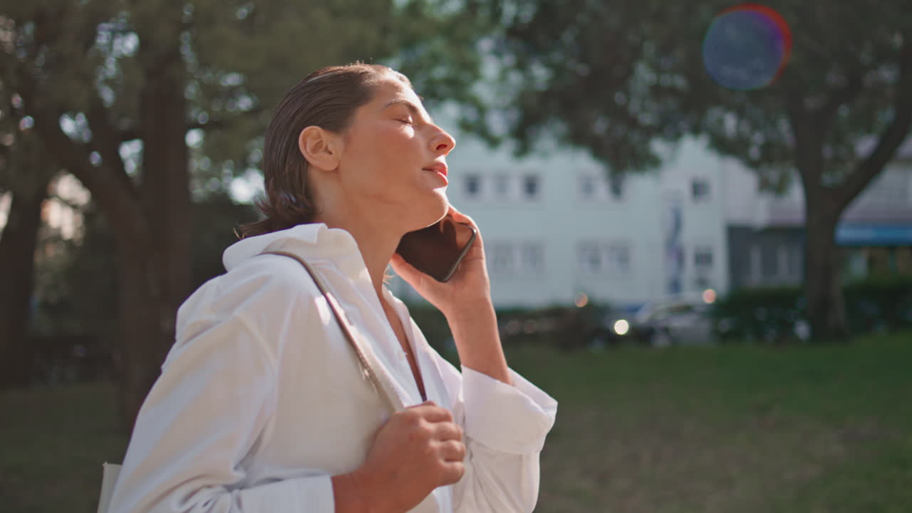 부동산 중개인 여성이 스마트폰을 사용하고, 골목길을 걸어가며, 근접 촬영을 하고, 여성이 드폰으로 전화하고 있다.