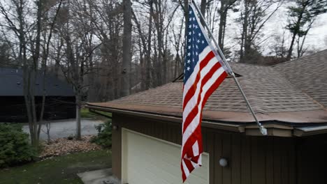 Girando-A-La-Izquierda-Alrededor-De-Una-Bandera-Americana-En-Una-Casa-En-Primavera-Nublada