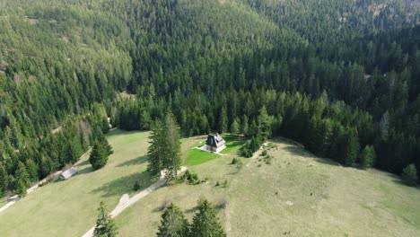 Drohnenaufnahmen-Fliegen-über-Ein-Hölzernes-Berghaus-Auf-Der-Spitze-Des-Hügels-Und-Einen-Kiefernwald-Im-Hintergrund