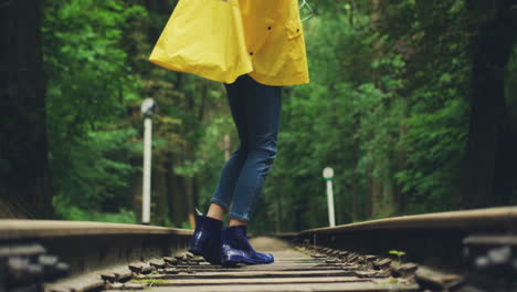 Nahaufnahme-Der-Weiblichen-Beine-In-Jeans,-Während-Die-Frau-Auf-Der-Eisenbahn-Im-Wald-Steht-Und-Sich-Am-Regentag-Herumdreht