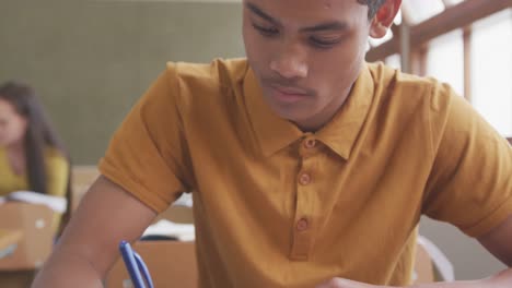 Mixed-race-boy-writing-in-high-school-class