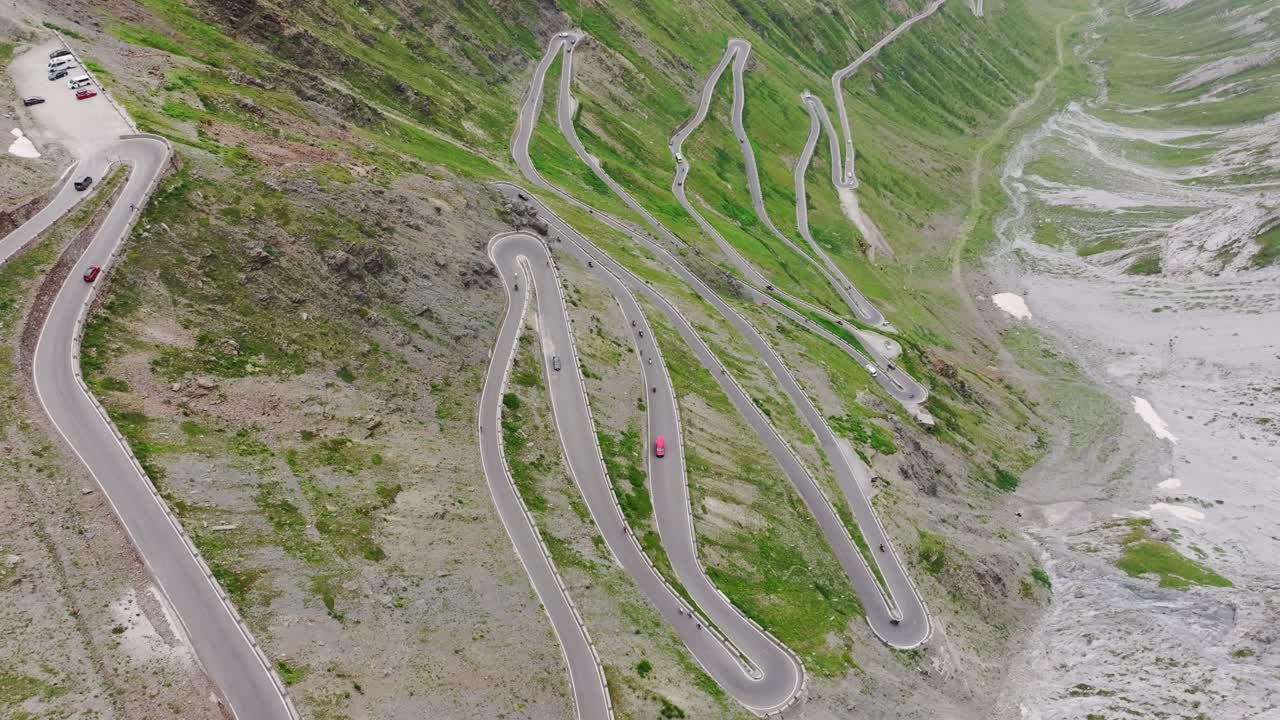 Curvy alpine pass with cars winding through Stelvio switchbacks in summer mist
