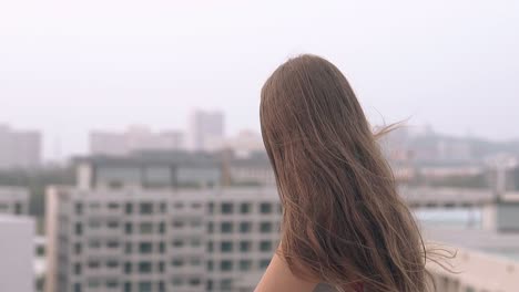 Chica-Sentada-En-El-Techo-De-Un-Edificio-Alto-Al-Atardecer-En-Cámara-Lenta