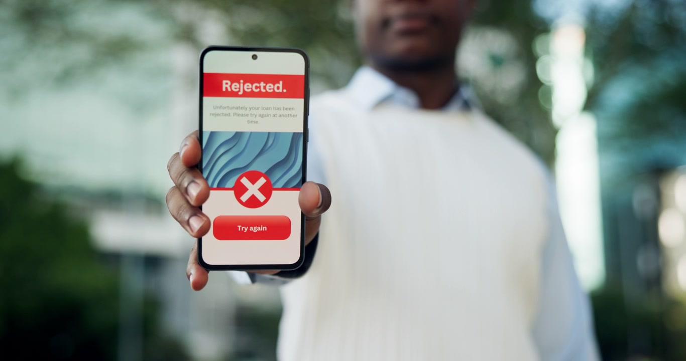 Uomo che tiene uno smartphone che mostra la notifica di rifiuto della domanda di prestito