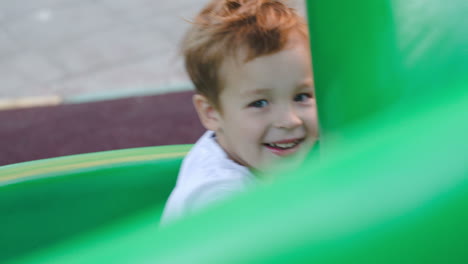 Niño-Feliz-En-El-Tobogán-Al-Aire-Libre