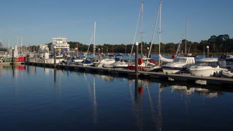 sped-up-shot-of-Wightlink-ferry-sailing-past-moored-up-motor-yachts-on-Lymington-river