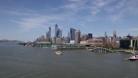 Luftaufnahme-Von-Hudson-Yards-Und-Chelsea-Piers,-Im-Sonnigen-Midtown,-New-York,-USA-–-Niedrig,-Verfolgung,-Drohnenaufnahme