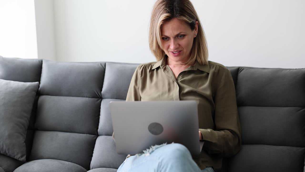 mujer trabajando en una computadora portátil en el sofá
