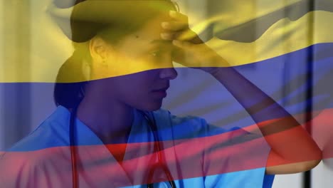 bandera de colombia ondeando contra una trabajadora de salud afroamericana estresada en el hospital