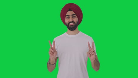 hombre indio sikh feliz mostrando el signo de la victoria pantalla verde