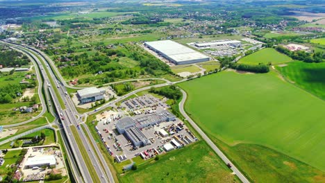 buildings of logistics center, warehouses near the highway, view from height, a large number of trucks in the parking lot near warehouse