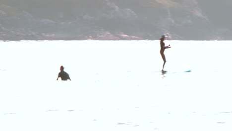 A-surfer-and-paddle-boarder-out-in-the-ocean-in-Tofino,-British-Columbia