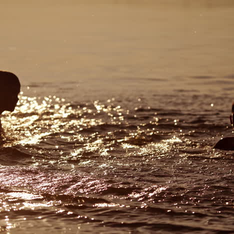 kids playing in the evening water background. two friends having fun together in the river while splashing with water outdoors.
