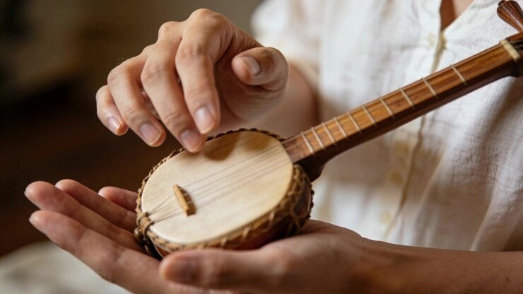 Plucking player's hands as right-hand fingers touch strings at home, practicing banjo, white shirt