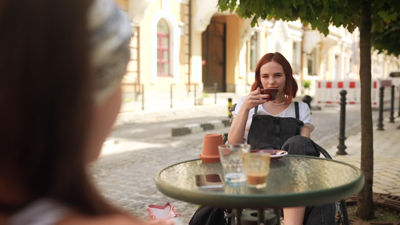 체어 에 앉은 여자 가 도시 카페 에서 커피 를 마시고 있다