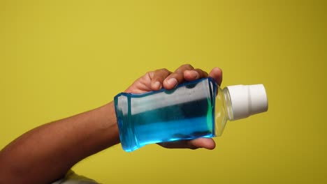 mano con una botella de enjuague bucal