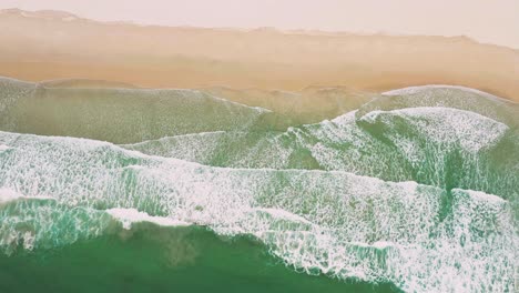 Aerial-views-of-flying-over-stunning-sandy-beach-with-tropical-waves-rolling-into-the-shore