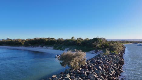drone captures serene gold coast seaway with boats and lush greenery under clear skies and warm sunset lighting