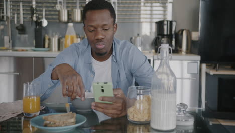 man having breakfast and using his smartphone