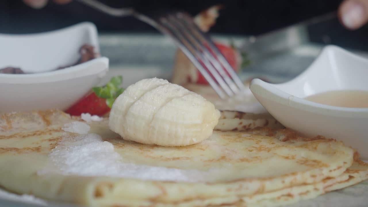 Eating Delicious Pancakes with Banana and Powdered Sugar