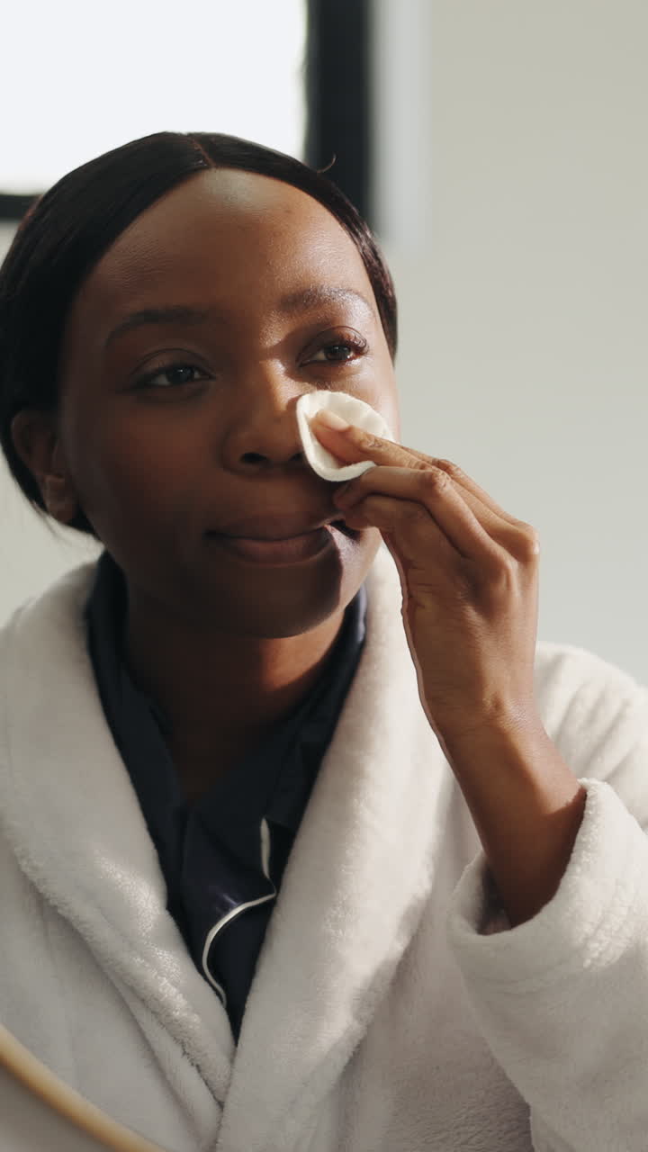 Smiling Black Woman Applying Skincare Product with Cotton Pad