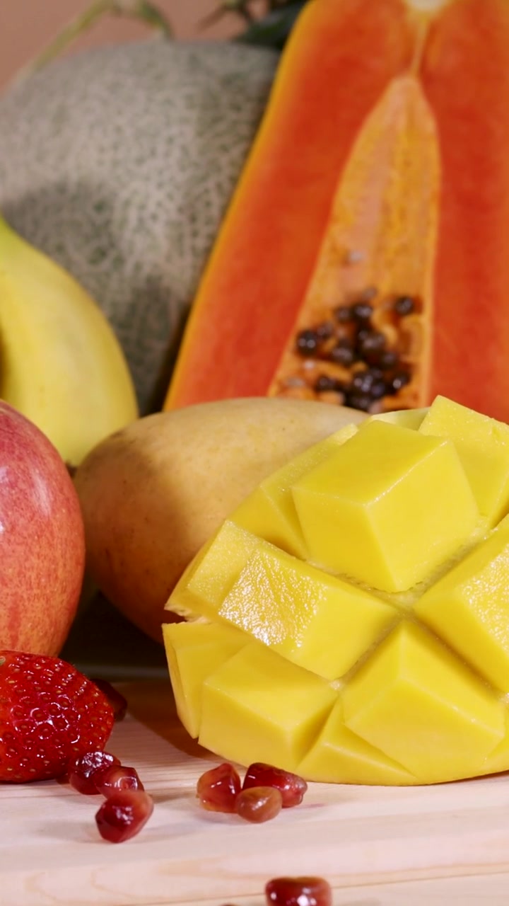 Un vibrante primo piano verticale che mostra papaya a fette con semi e un mango a cubetti intagliato a riccio