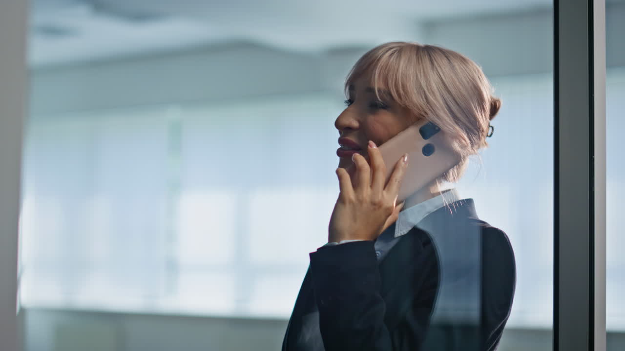 Smiling businesswoman calling smartphone in modern office building portrait