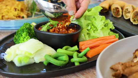 person serving chili dip with fresh vegetables