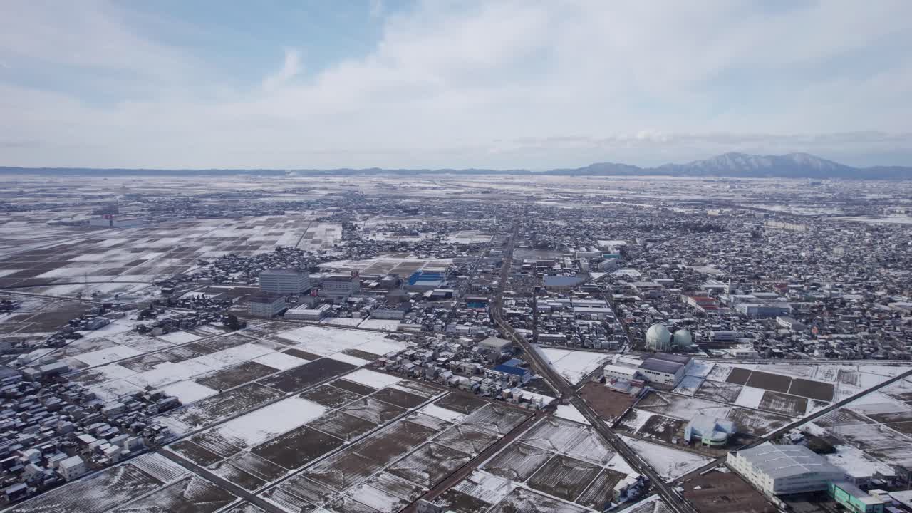 Drone view of suburban and agricultural areas under light snow cover in Japan
