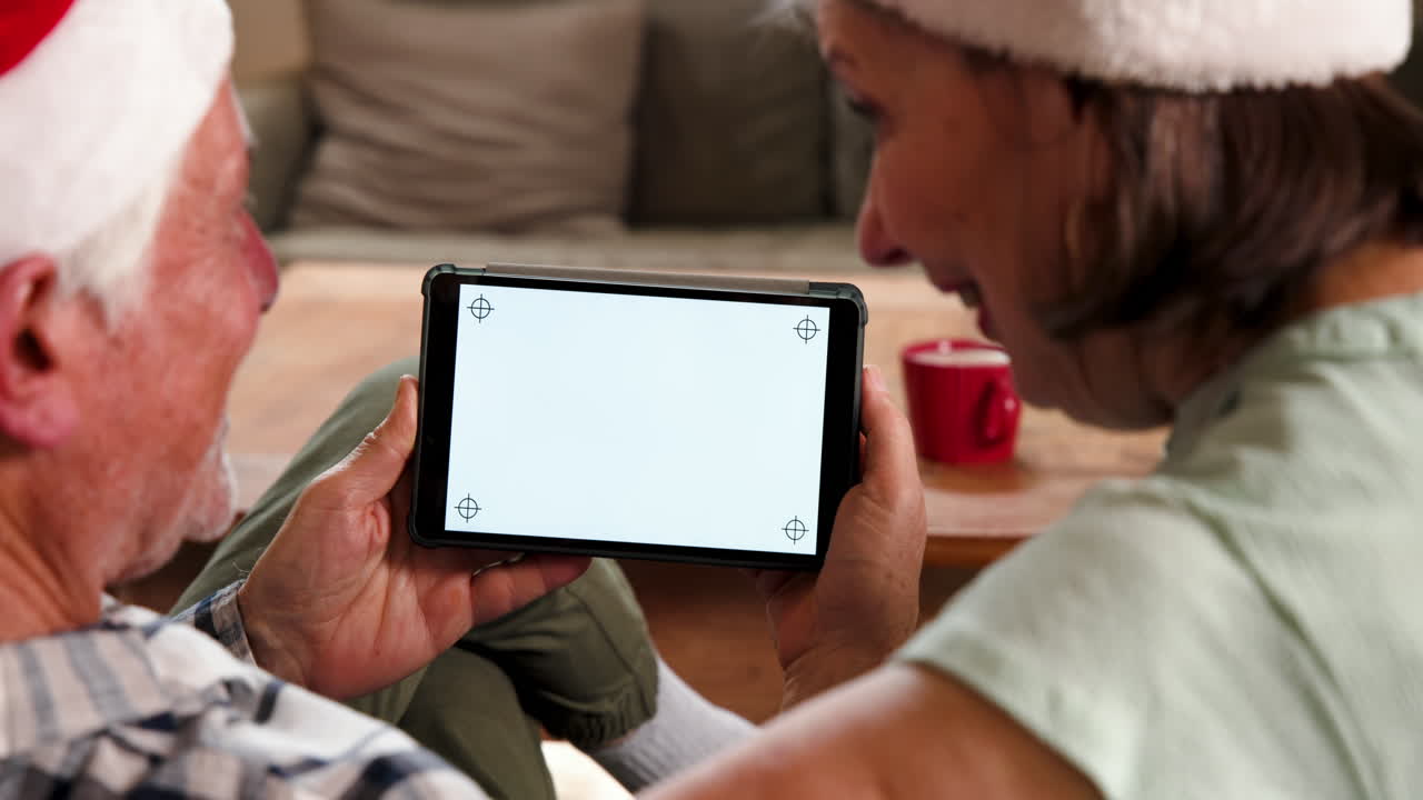Senior couple using tablet at home, enjoying cozy Christmas together