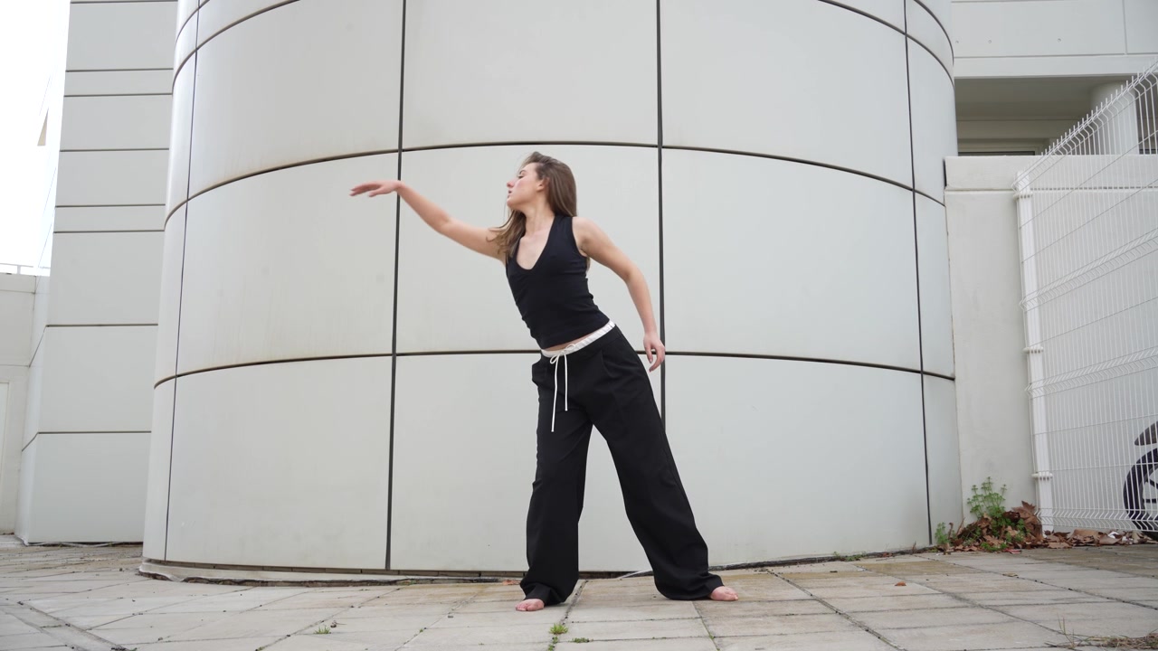 Una performance di danza si svolge sullo sfondo di un'architettura astratta, fondendo arte e movimento in modo unico.