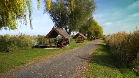 outdoor wooden shelters along a lakeside path in akasztó, hungary under clear autumn skies