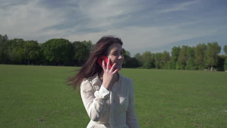 Foto-De-Steadicam-De-Una-Joven-Italiana-Hermosa-De-Muy-Buen-Humor-Mientras-Caminaba-Por-El-Parque-Y-Hablaba-Por-Teléfono