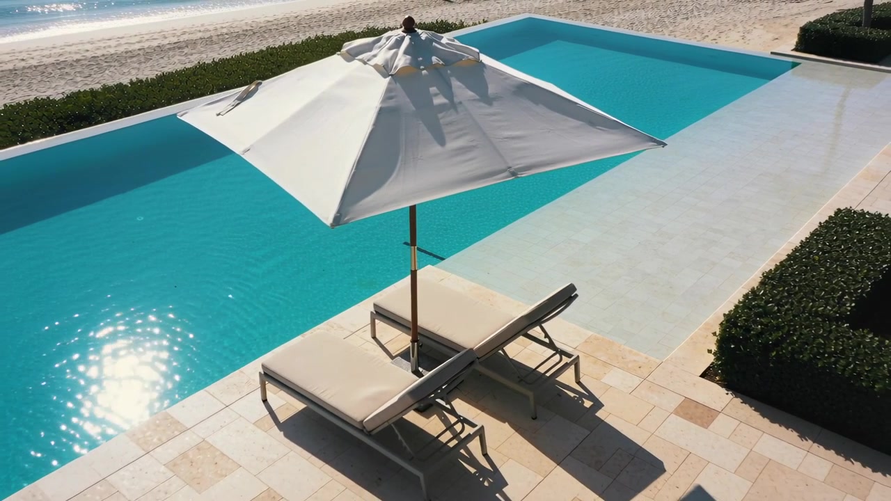 Approaching from poolside, man adjusting umbrella for shade at pool terrace, lounge chairs visible