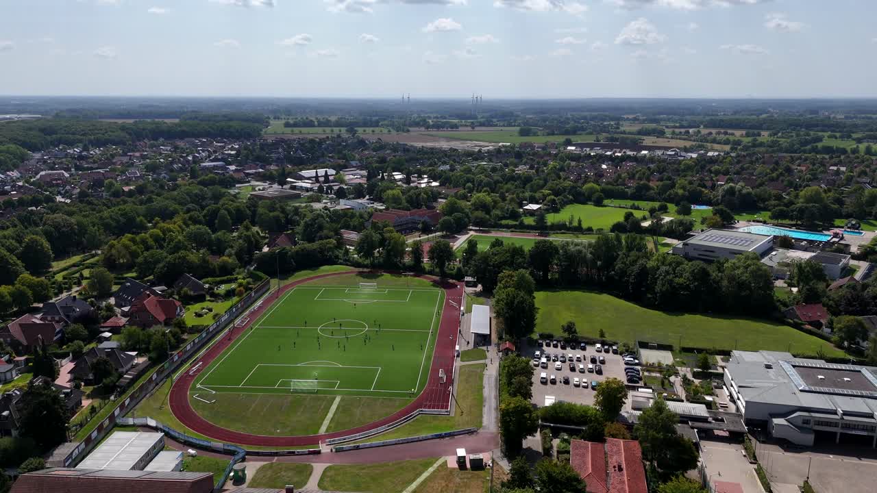 Soccer field of American town in summer. Housing area and neighborhood on hot sunny day. Aerial wide shot. Artificial grass field for football
