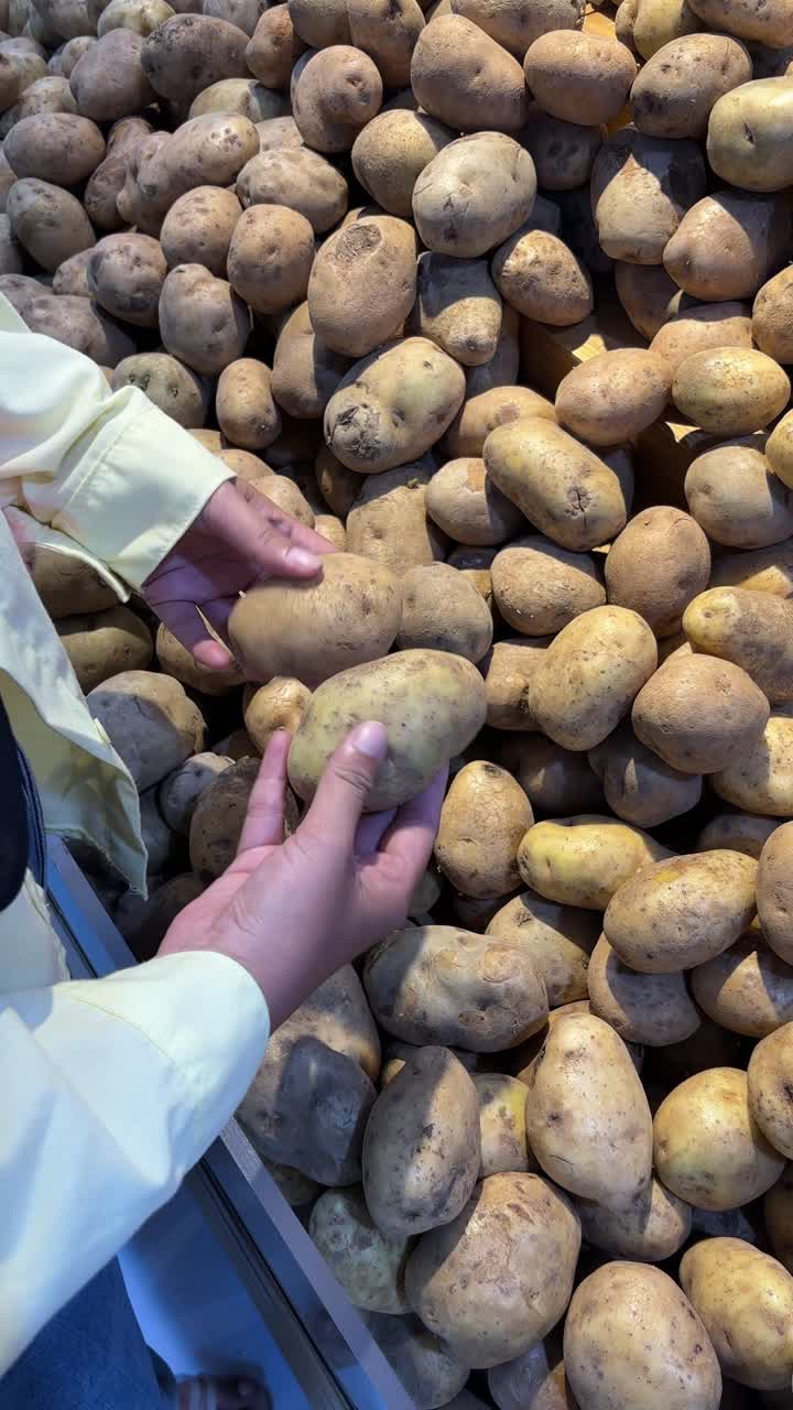 Persona che seleziona patate fresche nel reparto ortofrutta di un supermercato