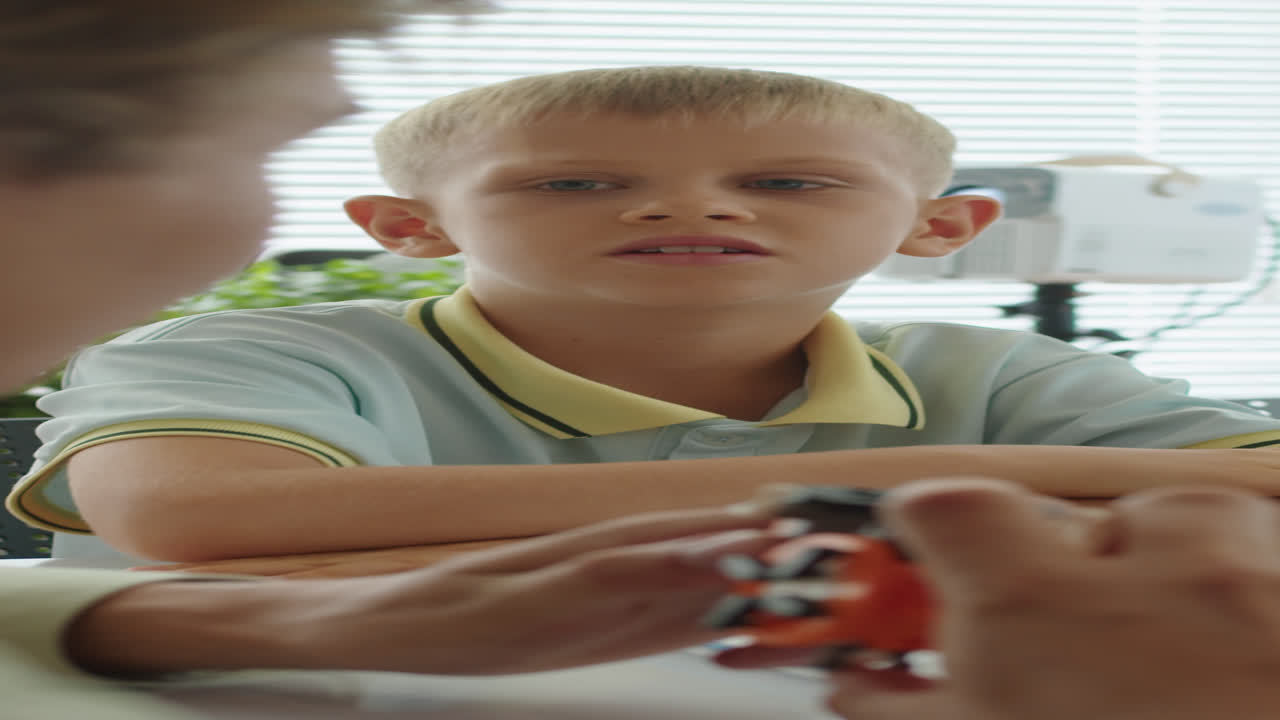 Schoolboy Listening to Tutor Holding Small Robot at Engineering Class