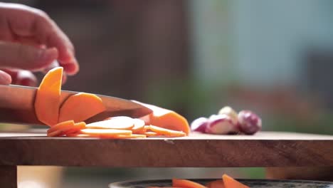 Preparing vegetables for cooking — a close-up shot of slicing orange carrots with precise knife work