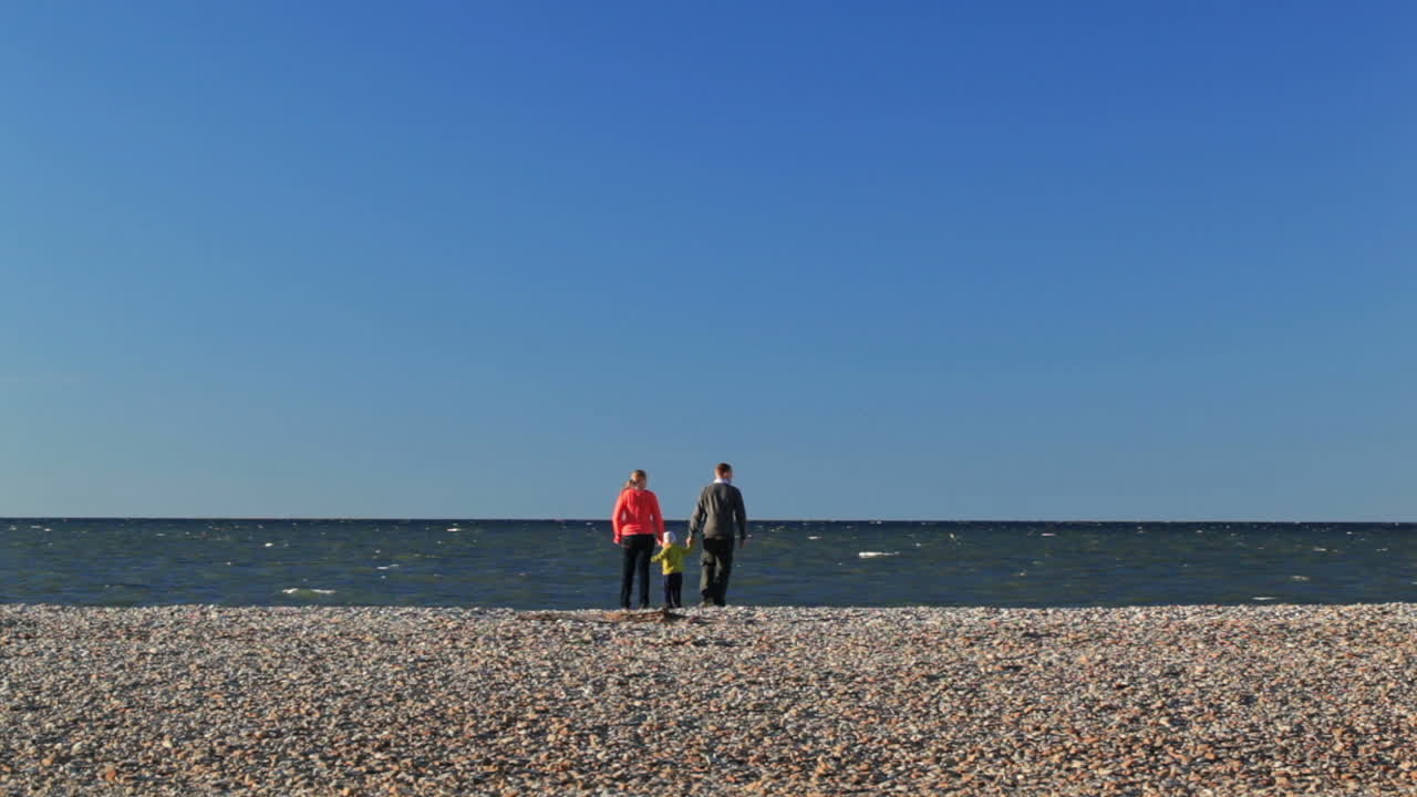 familia de tres en la playa de guijarros