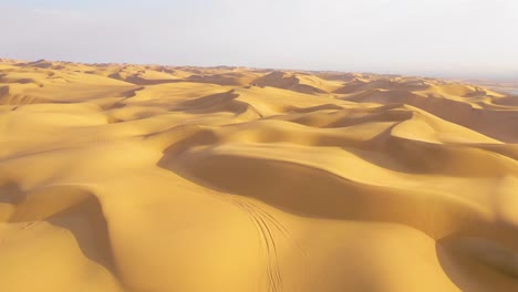 Astonishing-aerial-shot-over-the-vast-sand-dunes-of-the-Namib-Desert-ends-at-a-safari-van-and-people