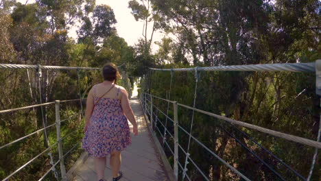 una mujer con un vestido cruzando el puente colgante de la calle spruce en san diego, california