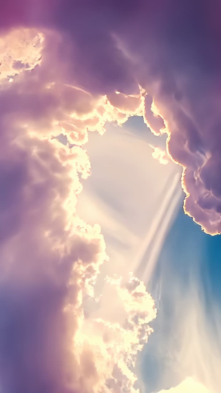 Vertical video: Shifting cumulus clouds revealing central gap aloft, sending sunbeams and blue sky