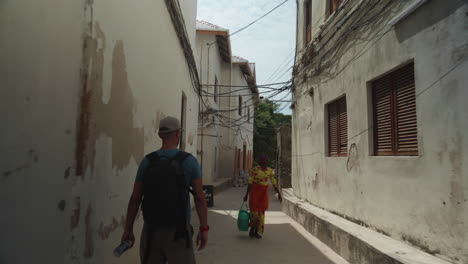 tourist with a backpack walking in the narrow streets of zanzibar stone town.
