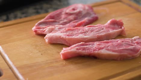 seasoning lamb chops with salt and pepper on a cutting board