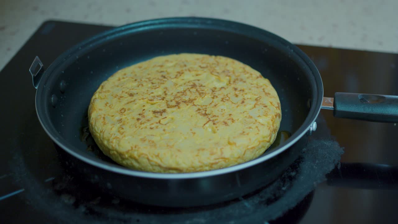 una tortilla de patata en movimiento cocinando en una sartén