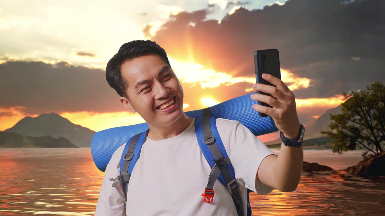 Close Up Of Asian Male Hiker With Mountaineering Backpack Showing Peace And Thumbs Up Gesture While Taking A Selfie At A Lake