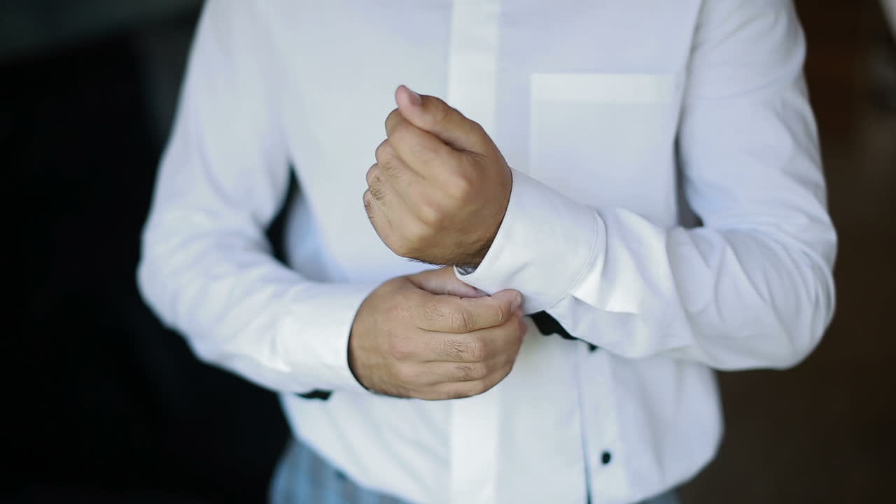 Businessman dresses white shirt, male hands close up. Groom getting ready in the morning before wedding ceremony