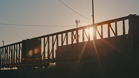 freight train moving in slow motion during golden hour with sun flares shining through train carts cinematic