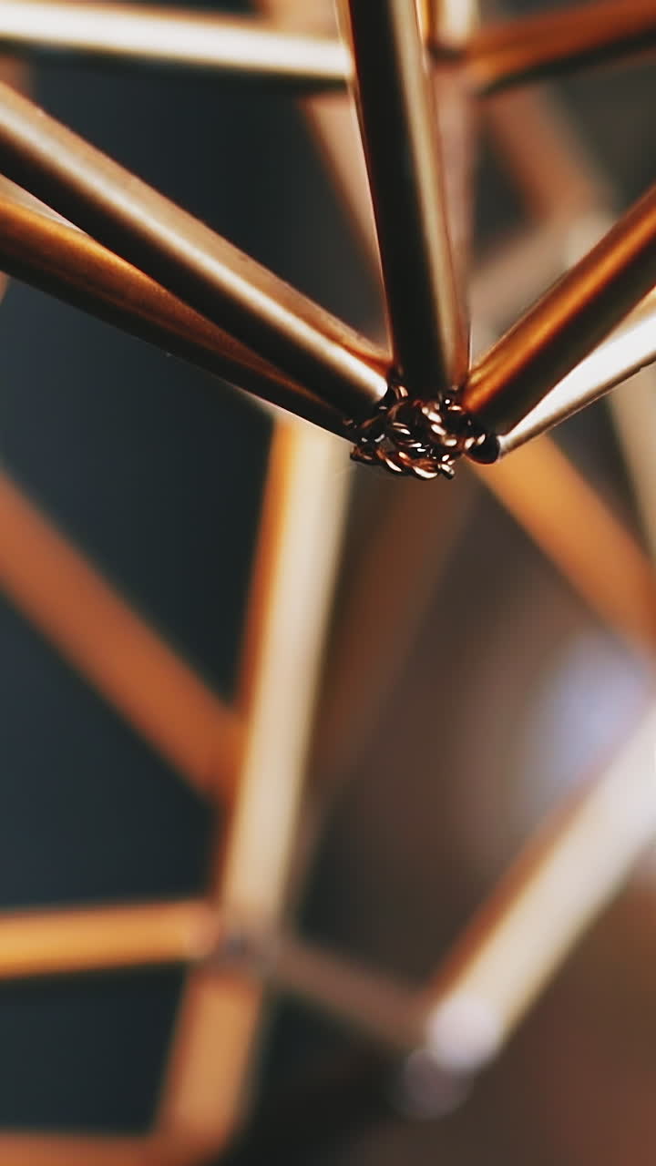 CU, slow motion: stylish golden steam-punk metal luster and light bulb hang on ceiling in spacious room against blurred background close view